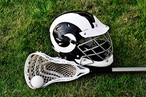 A lacrosse helmet, stick, and ball sitting on the ground