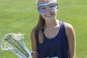 A girl smiling and holding lacrosse stick